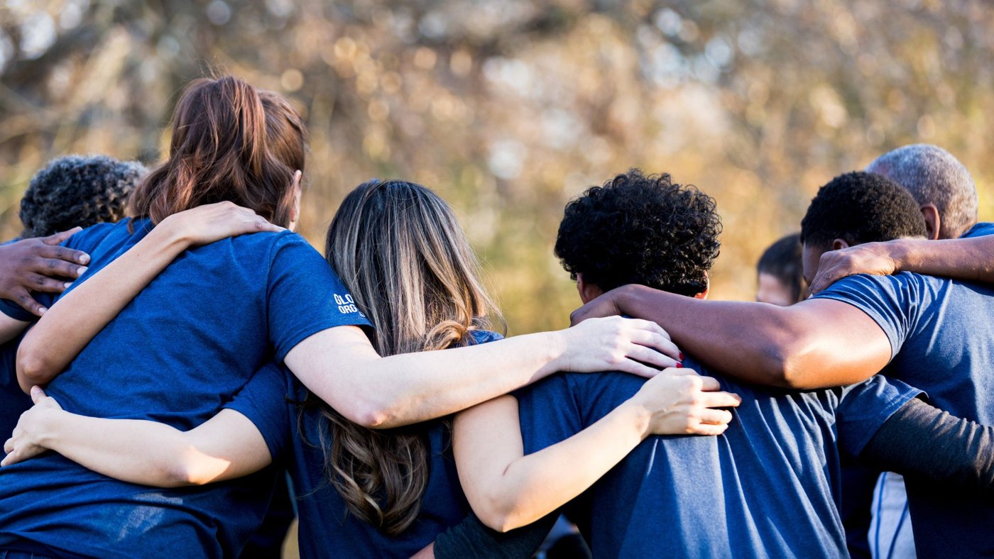 A team standing together arm in arm outdoors